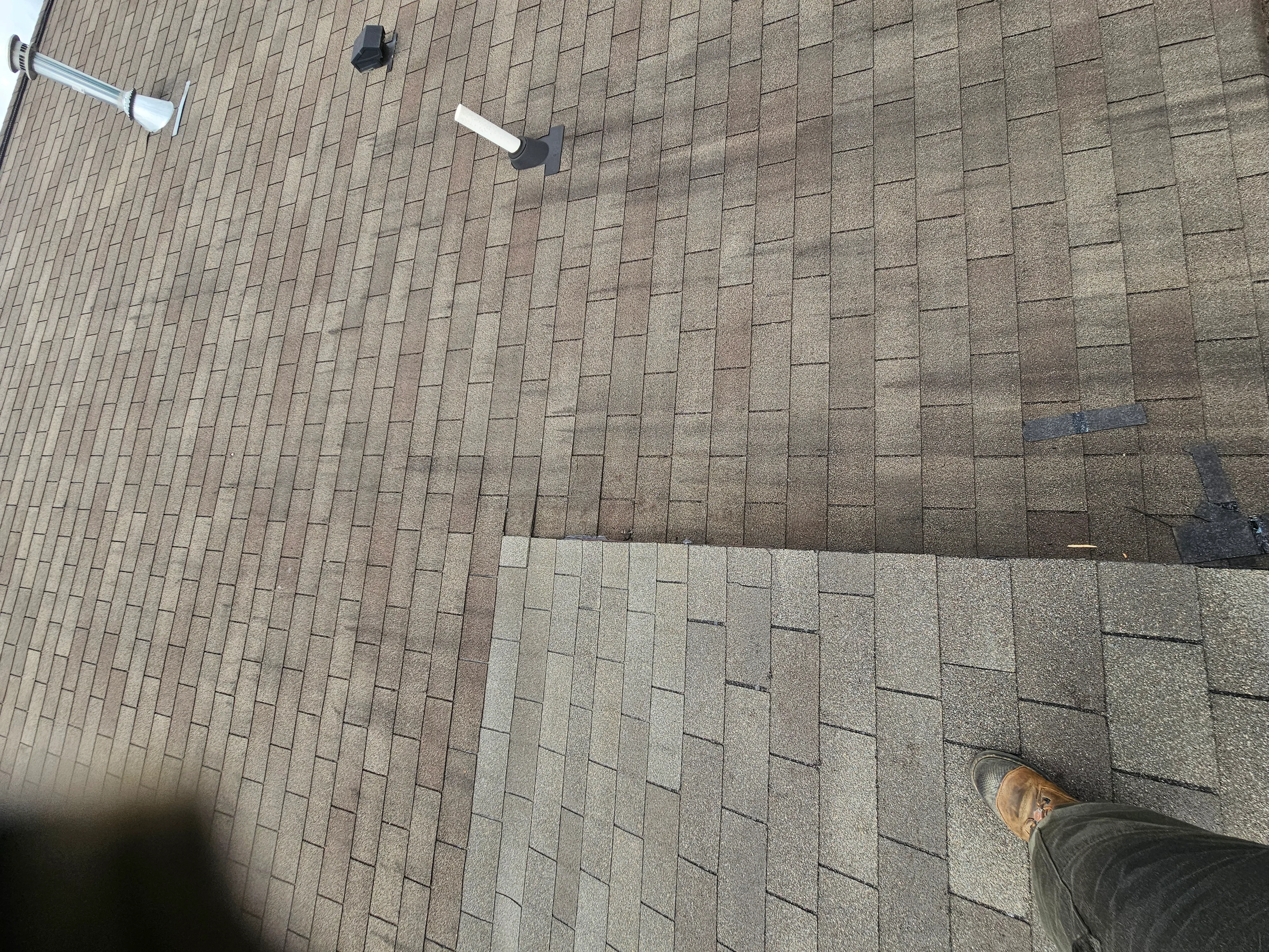 Newly installed asphalt shingle roof with staggered pattern and roof vents