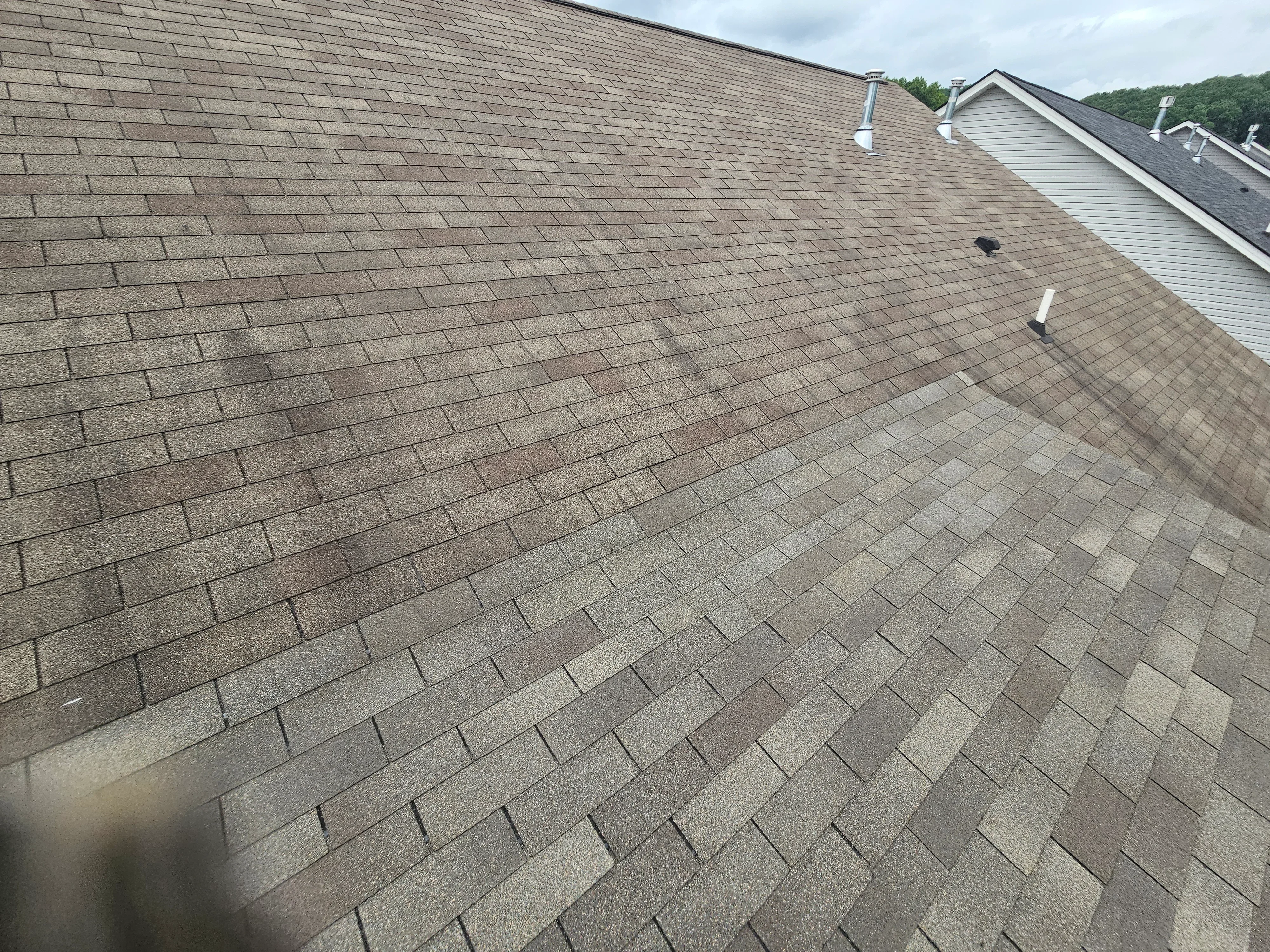 Newly installed asphalt shingle roof with gray dimensional shingles, roof vents, and metal flashing