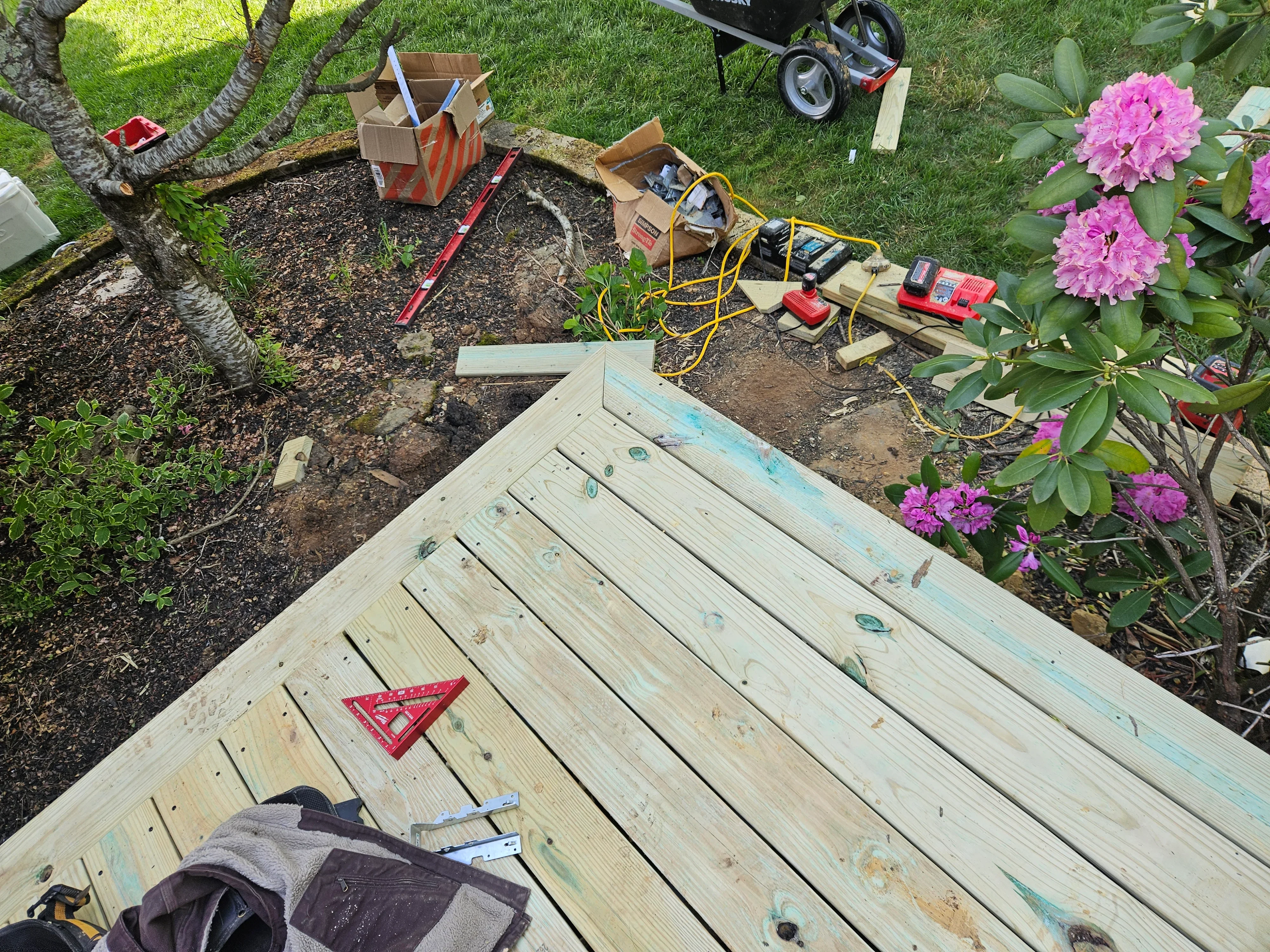 Pressure-treated wood deck framing with fasteners and construction tools on-site