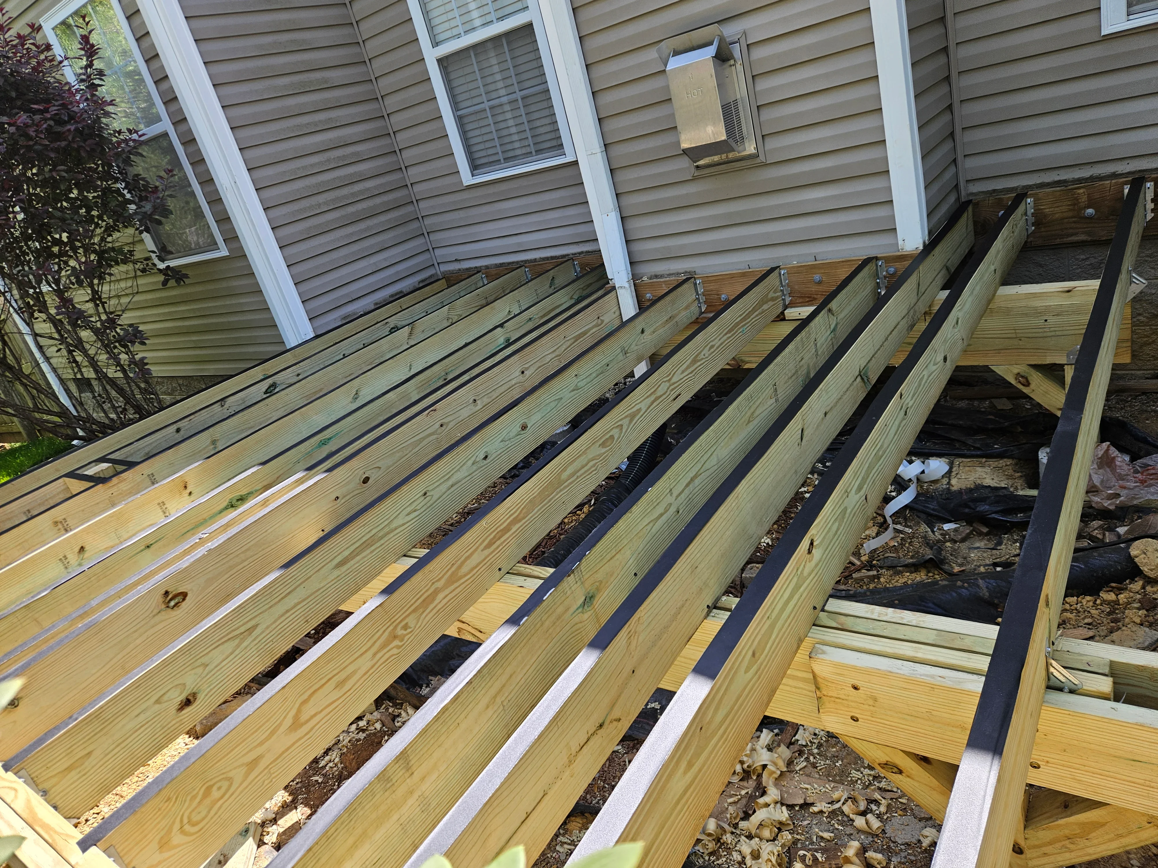 Pressure-treated wood deck joists and beams with metal flashing during framing installation