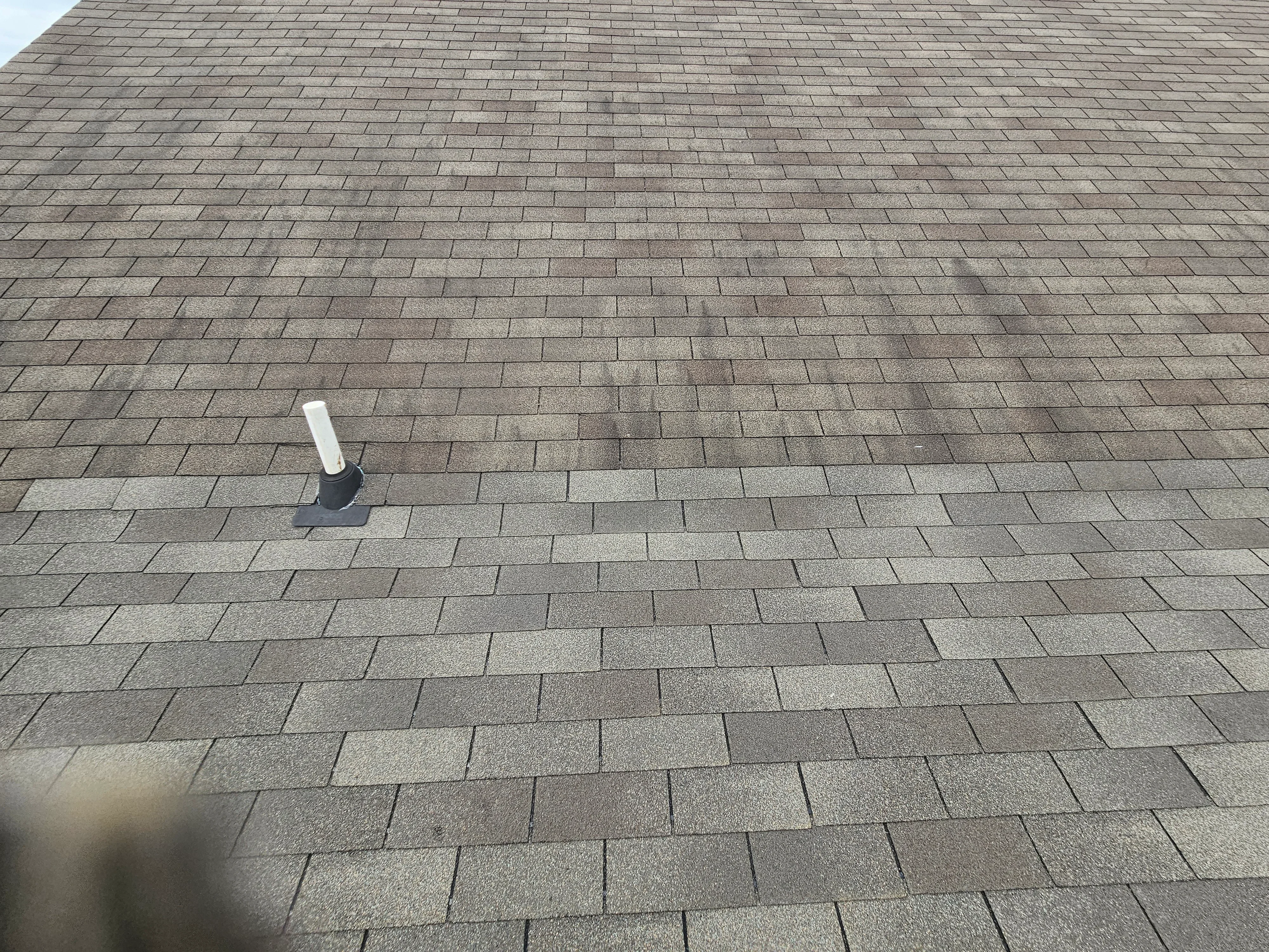 Gray dimensional asphalt shingles installed in staggered pattern with roof vent and flashing