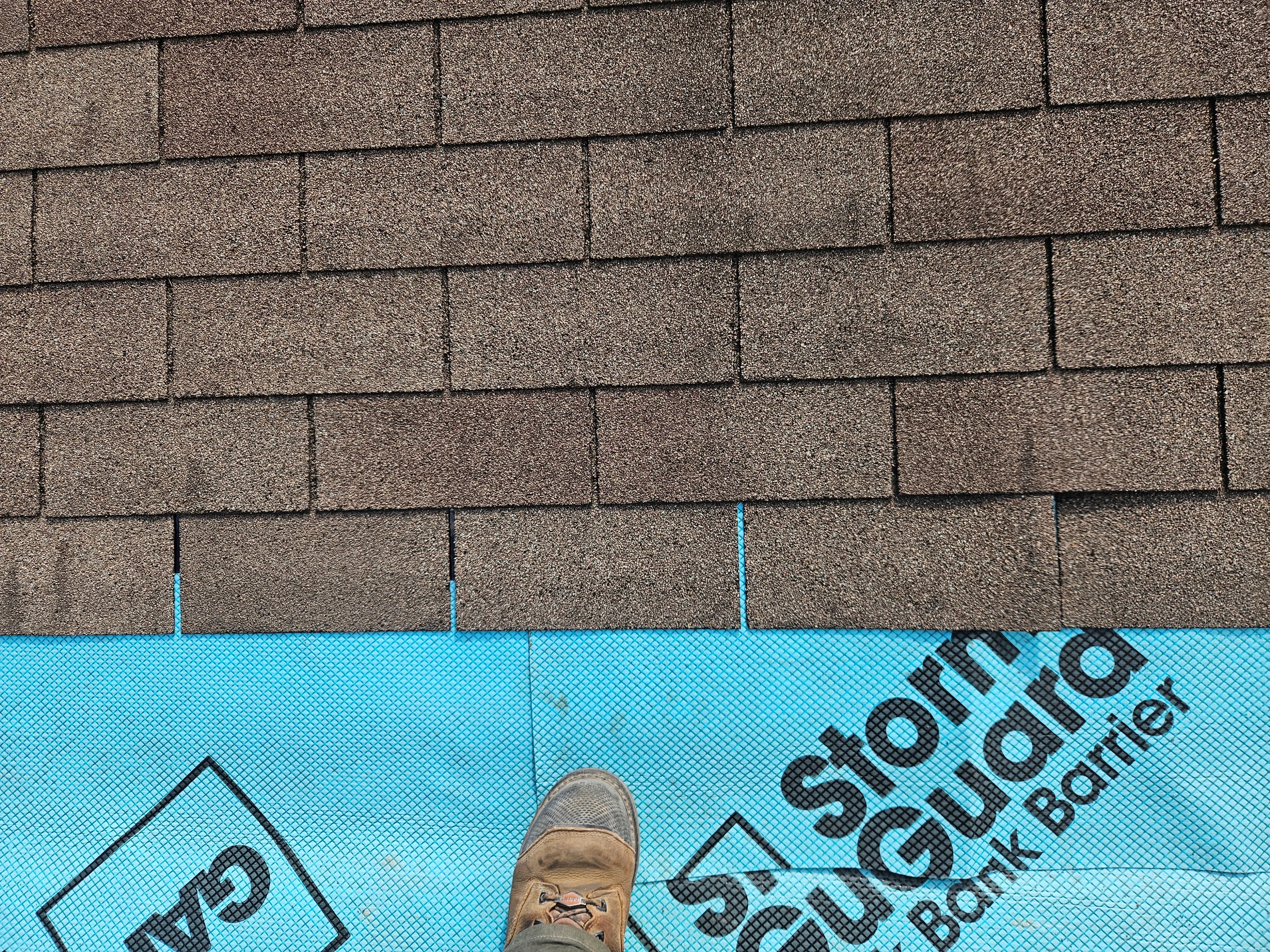 Asphalt shingle roof installation with gray dimensional shingles and blue underlayment