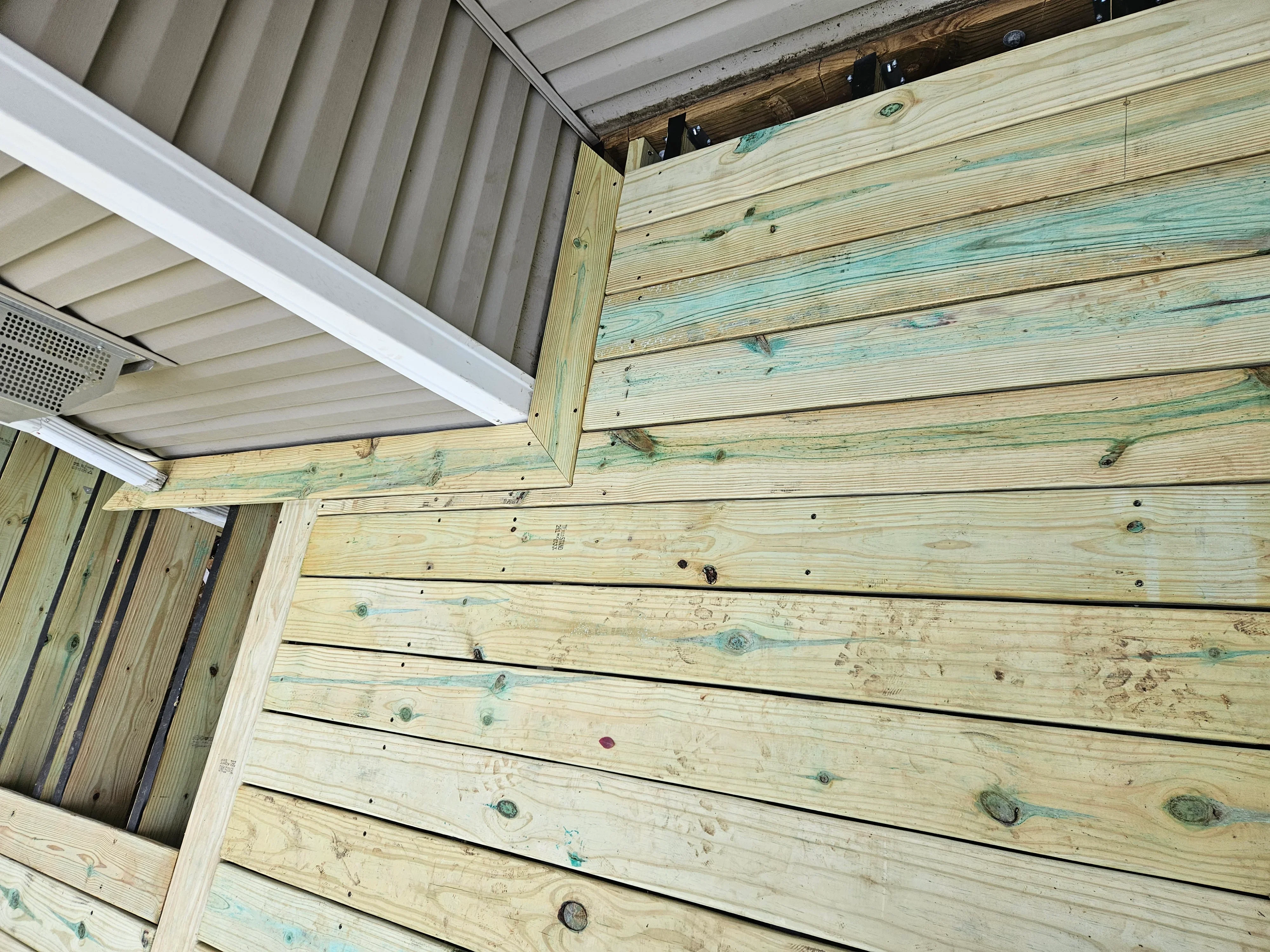 Pressure-treated deck framing with lumber joists, beams, and white trim fascia