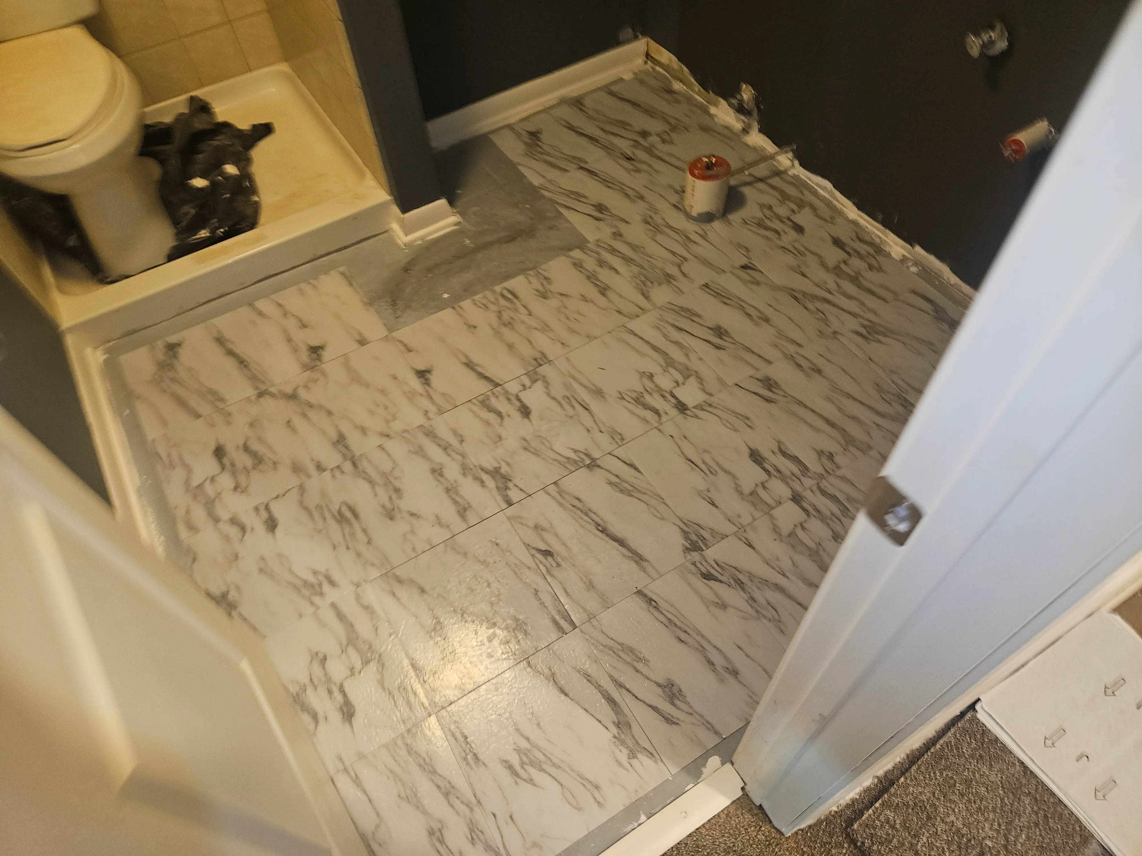 Marble-look porcelain tile bathroom floor with gray veining and grout lines
