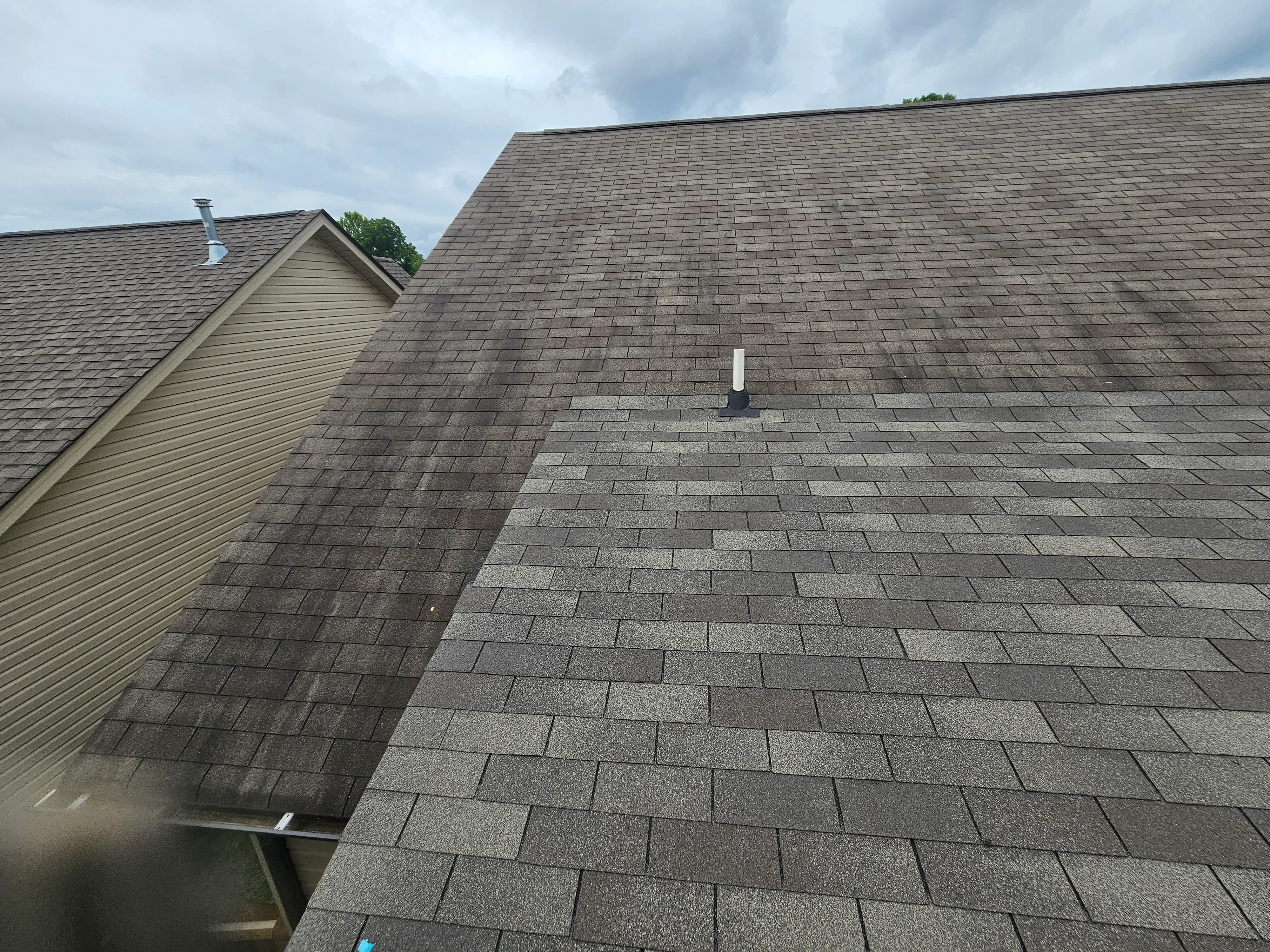 Newly installed gray architectural shingles on pitched roof with proper overlap and flashing
