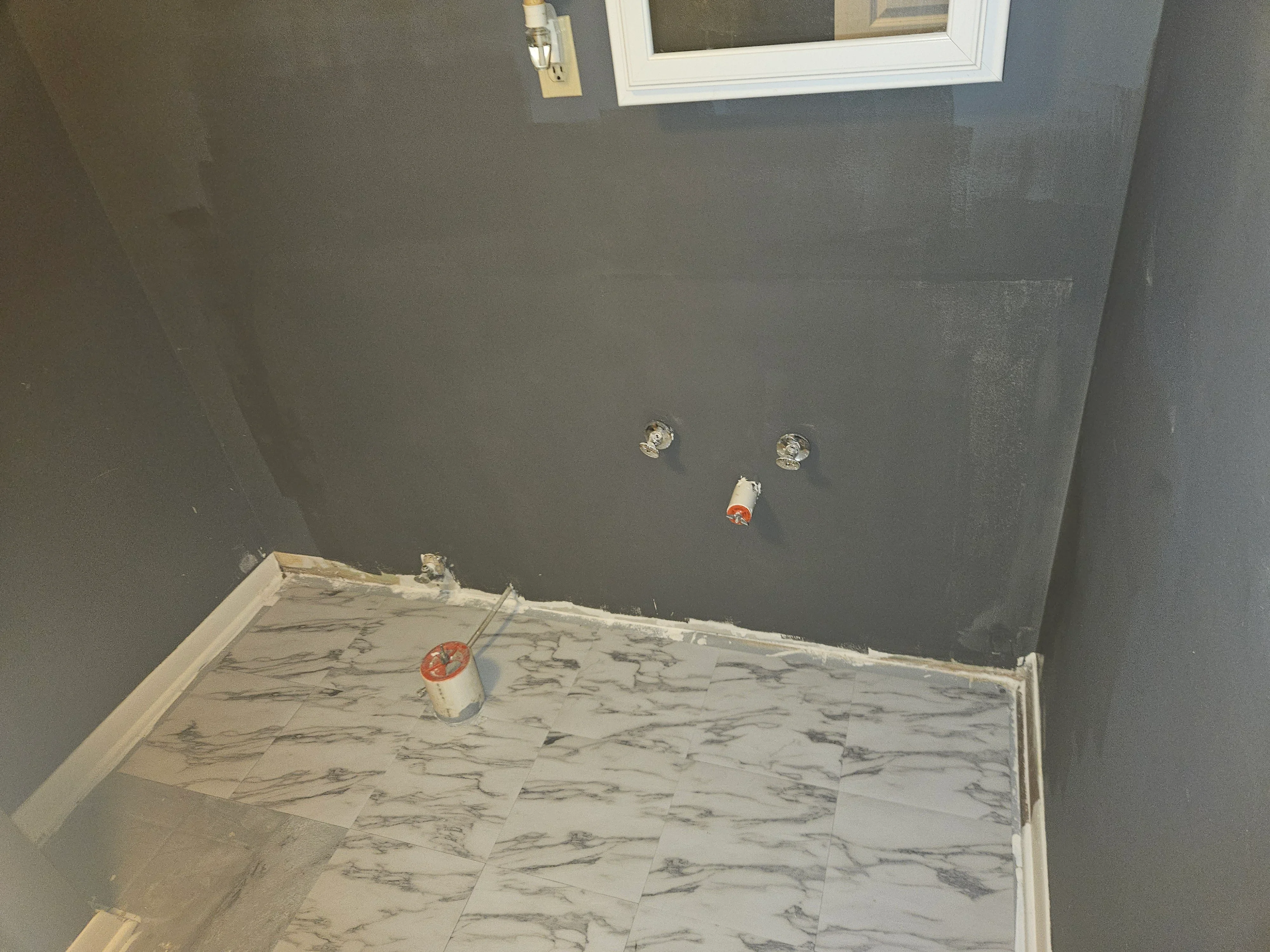 Marble-look tile floor with white trim, drywall walls, and electrical rough-in during bathroom renovation
